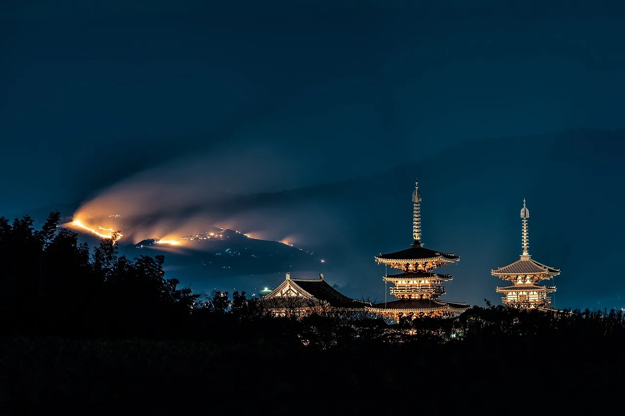podświetlone świątynie nocą w Japonii, w tle góry