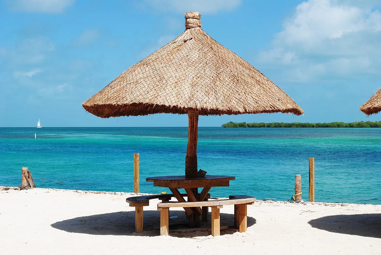 słomiany parasol z ławkami oraz stolem na plaży w Belize