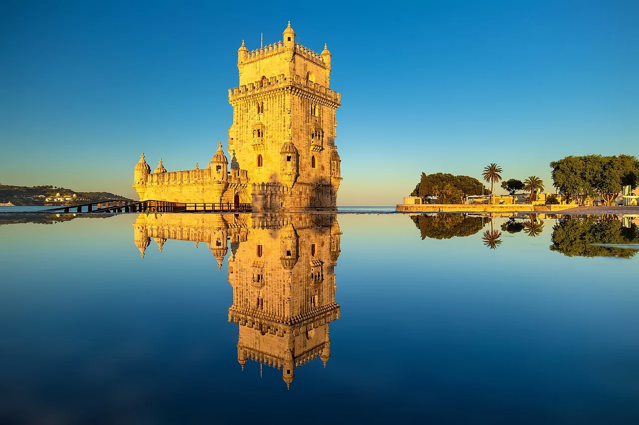 tafla wody odbijająca niesamowitą wieżę Torre de belém pokrytą złotym promieniem słońca