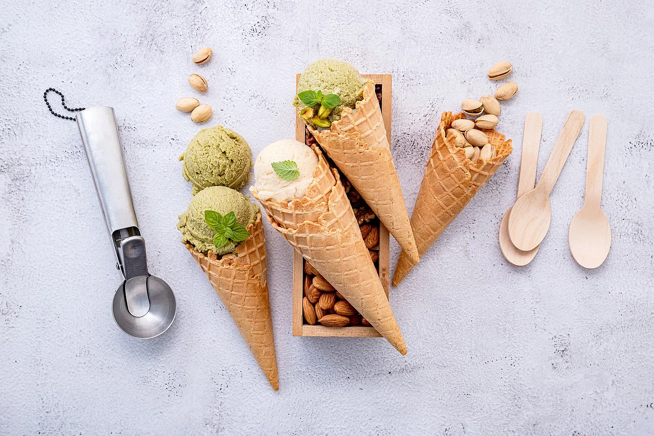 Lody w różnych smakach serwowane w rożkach, z użyciem łyżki do lodów, idealne jako zamrożony deser.