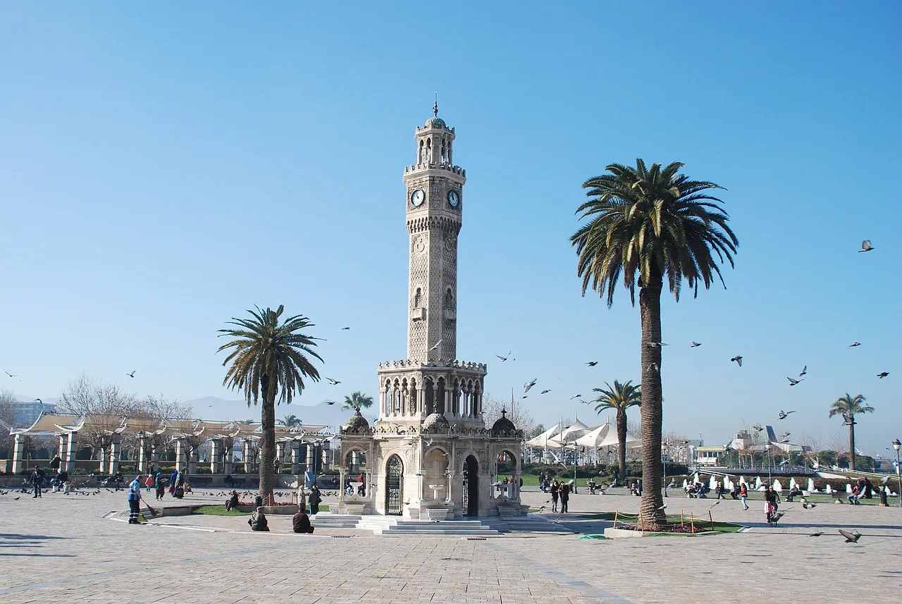 Wieża zegarowa, dwie palmy, ptaki latające wokół, Izmir