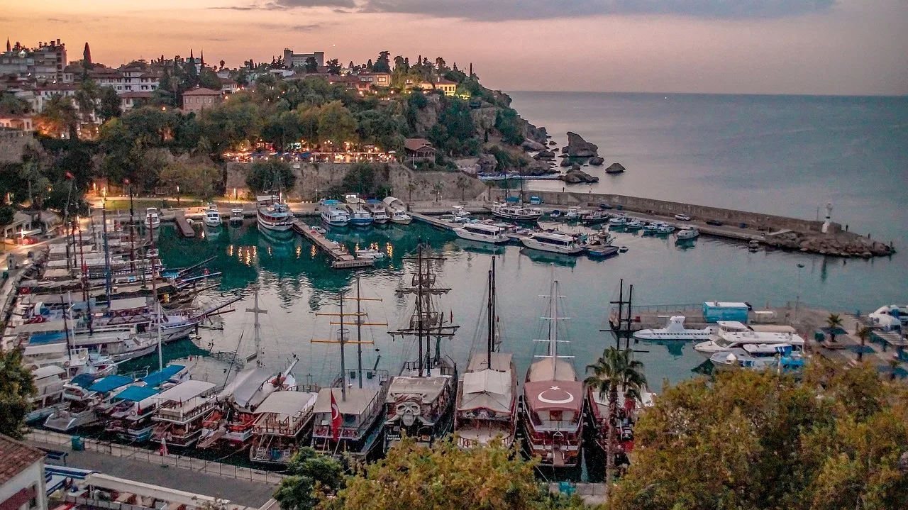 Port w Antalya, Turcja, o poranku, z zacumowanymi łodziami i widokiem na morze.
