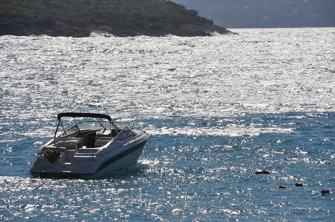 Plaża Ksamil w Albanii z krystaliczną wodą, falami i łodzią, idealna na letnie wakacje.