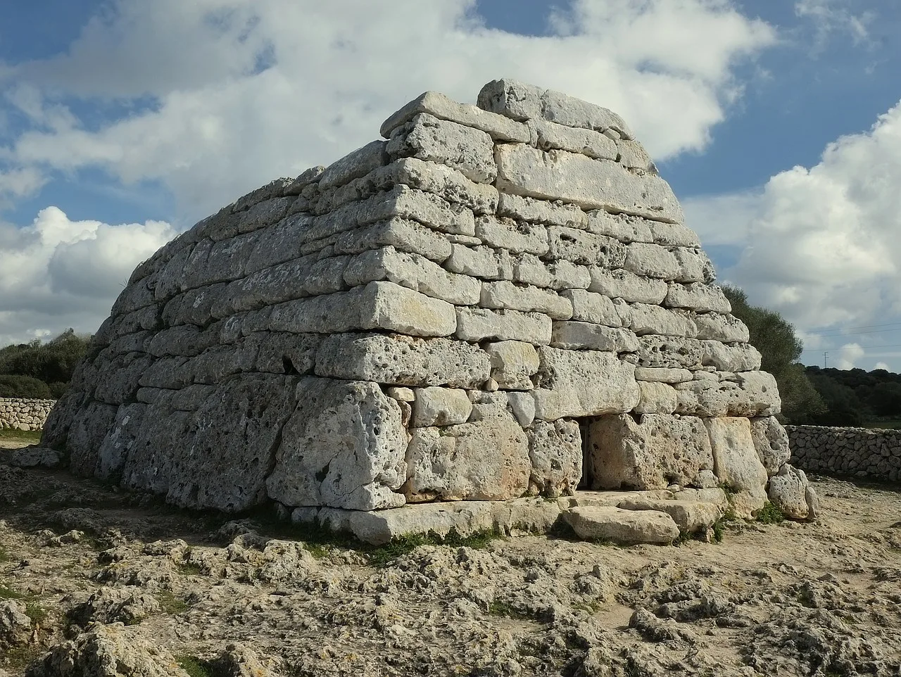 Prehistoryczny talayot na wyspie Minorca, przedstawiający kamienny megalit w historycznym krajobrazie.