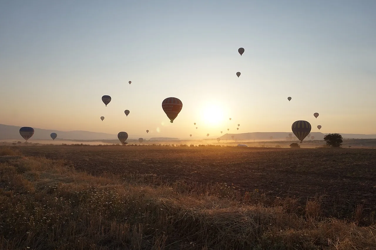 Balony unoszące się nad krajobrazem Kapadocji w Turcji podczas porannego lotu balonem.