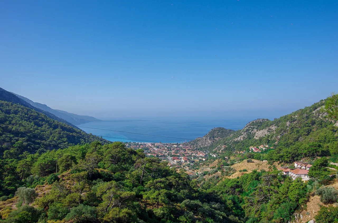 Widok na malowniczą plażę w Ölüdeniz, Fethiye, z zatoką otoczoną lazurowym morzem i górami w tle.