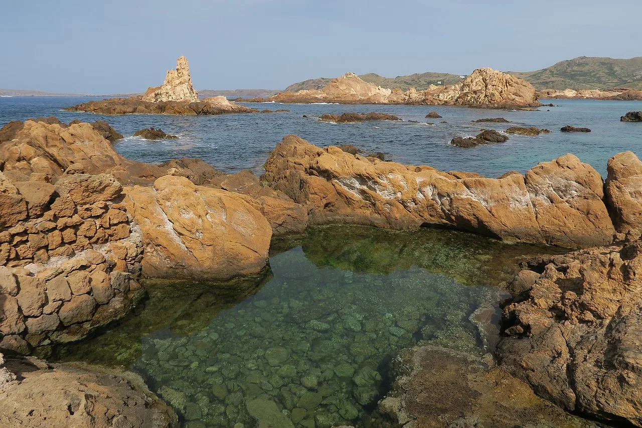 Plaża Cala Prégonda na Minorce z skalistym wybrzeżem, turkusową wodą Morza Śródziemnego i dziewiczym krajobrazem.