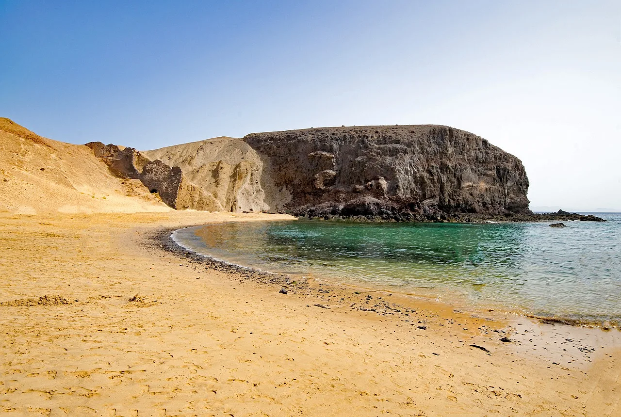 Plaża Playa del Papagayo w Lanzarote z piaszczystym wybrzeżem, skałami i turkusowym morzem, idealna na wakacje i letni wypoczynek.